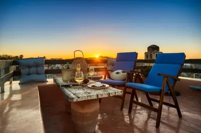 a patio with a table and chairs and a sunset at La Barchetta Old Town Home with Seaview in Chania Town