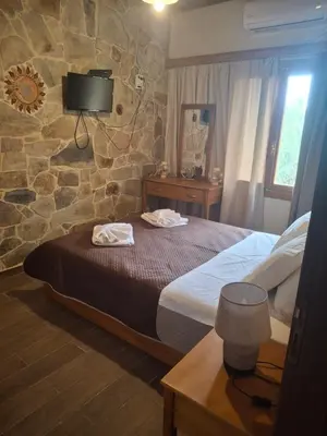 a bedroom with a large bed and a stone wall at Elafonisi House in Livadia