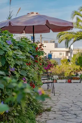 an umbrella and benches in a garden with flowers at Saint Trope Studios in Kalamaki Chanion