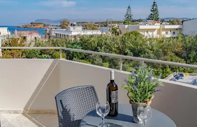 a table with a bottle of wine and glasses on a balcony at Saint Trope Studios in Kalamaki Chanion