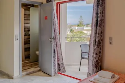 a bedroom with a door open to a balcony at Saint Trope Studios in Kalamaki Chanion