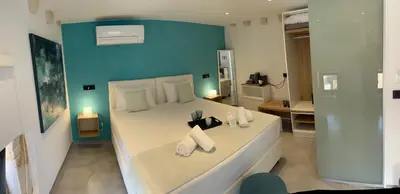 a bedroom with a large white bed with a blue wall at Antica Canea Luxury Rooms in Chania Town