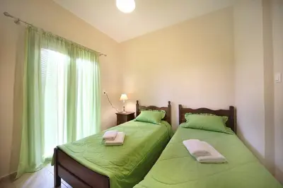 two beds in a room with green sheets and a window at Sfakia Thea Apartments in Sfakiá