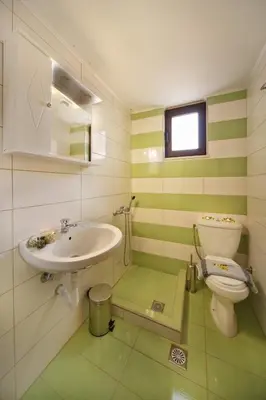 a green and white bathroom with a sink and a toilet at Sfakia Thea Apartments in Sfakiá