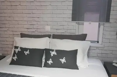 a white bed with four pillows and a brick wall at E&G Relax Homes-E in Kissamos