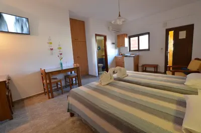 a bedroom with a large bed and a kitchen at Kochyli Studios in Palaiochóra