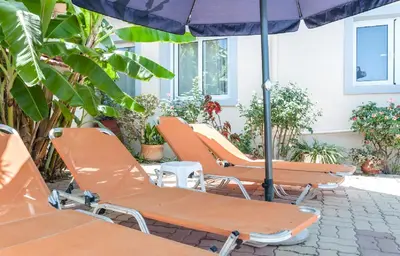 a row of orange lounge chairs and an umbrella at Despina Villa in Agia Marina Nea Kydonias
