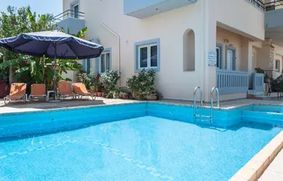 a swimming pool with an umbrella next to a house at Despina Villa in Agia Marina Nea Kydonias