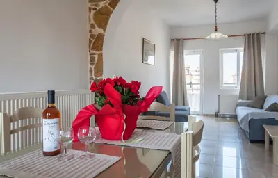 a table with a bottle of wine and red flowers on it at Despina Villa in Agia Marina Nea Kydonias