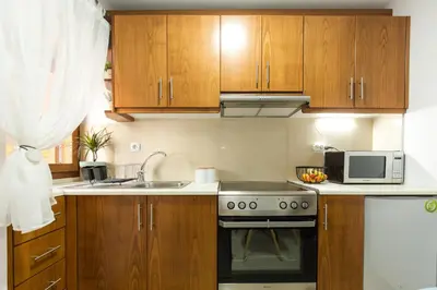 a kitchen with wooden cabinets and a stove and a microwave at Anastasia’s House in Kissamos