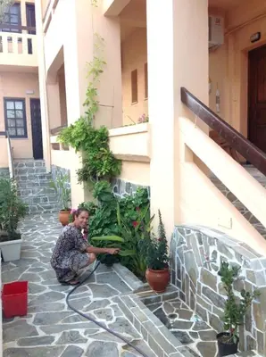 a woman sitting on the ground next to plants at Ilias Apartments in Plataniás