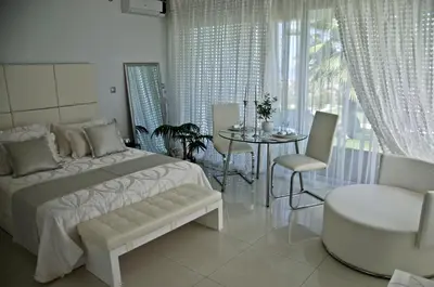 a white bedroom with a bed and a table and chairs at Reveli Estate in Kalathas