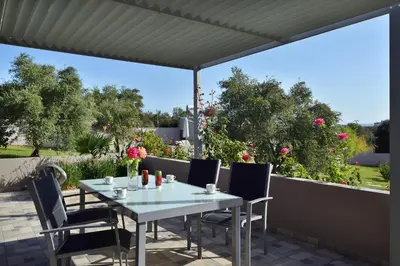 a white table and chairs on a patio at Alexandra's Garden Houses in Stalos