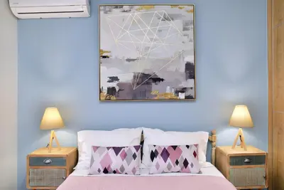 a bedroom with a blue wall with a bed and two lamps at Alexandra's Garden Houses in Stalos