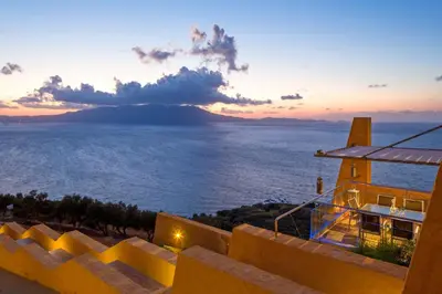 a view of the ocean at sunset from a house at Athina Epavlis - Ethereal Charm of Blue Horizons in Ravdhoúkha