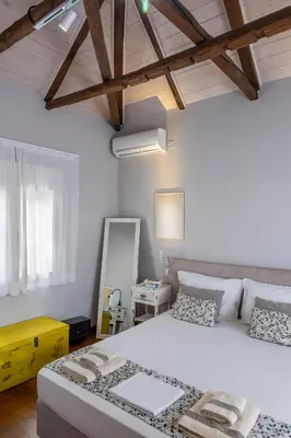 a bedroom with a large white bed and wooden ceilings at Casa Chrysa Chania 1st floor house with amazing view in Galatás