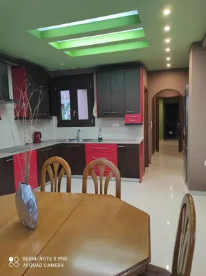 a kitchen with a wooden table and a kitchen with red cabinets at Homieland Souda in Souda