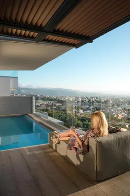 a woman sitting on a couch next to a swimming pool at NV Illusion in Chania Town