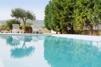 a swimming pool with blue water and chairs and trees at Villa Anthira in Ropanianá