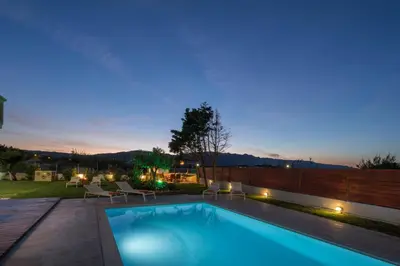 a swimming pool in a backyard at night at Villa Anthira in Ropanianá