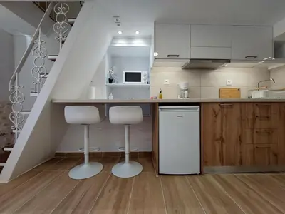 a kitchen with white cabinets and a counter with stools at Evans House II One Bedroom Maisonette in Chania Town