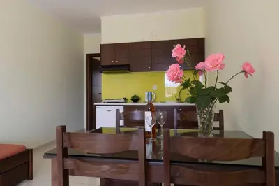 a kitchen and dining room with a glass table with pink flowers at Sandy Suites in Kalamaki Chanion