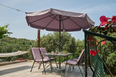 a table and chairs with an umbrella on a balcony at Batilas Garden House in Kissamos