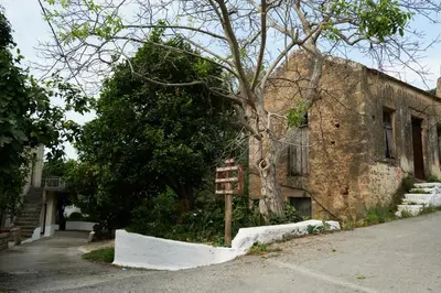 a brick building with a sign in front of a tree at Batilas Garden House in Kissamos
