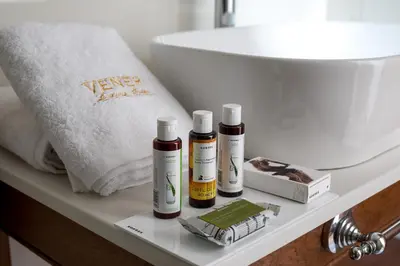 three bottles of essential oils sitting on a shelf next to a toilet at Vener Luxury Suites in Chania Town