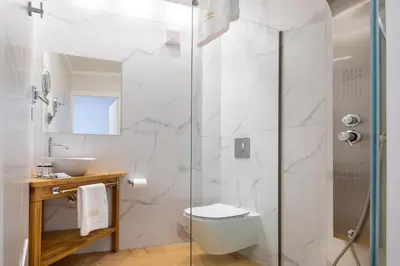 a bathroom with a toilet and a glass shower at Vener Luxury Suites in Chania Town