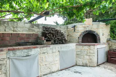 an outdoor brick oven with a pile of wood at Orange Tree Garden vacation home in Ayiá