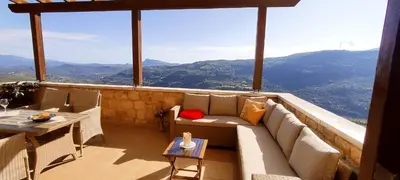 a balcony with a couch and a table and mountains at Vasiliki's Residence - Breathtaking View in Kissamos