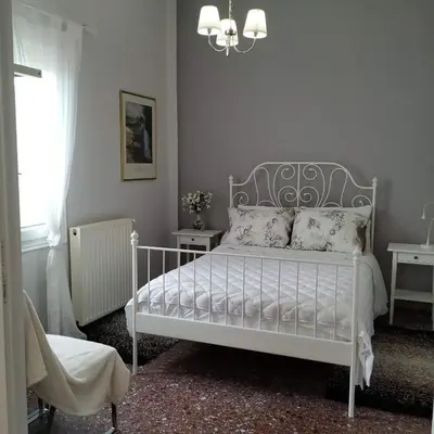 a bedroom with a white bed with pillows and a chandelier at Sunday Apartment Chania 2A in Chania Town
