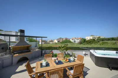 a patio with a table and chairs and a hot tub at Sun Ray Beach Life Villa in Agia Marina Nea Kydonias
