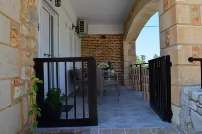 a balcony with a black gate and a chair at MV House Agia Marina in Agia Marina Nea Kydonias