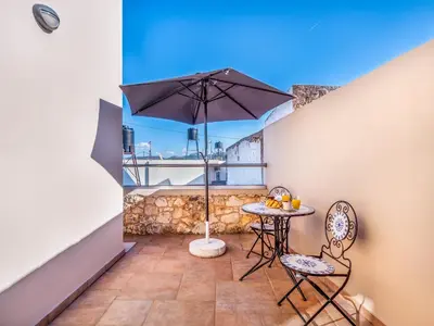 a balcony with an umbrella and a table and chairs at Casteli Stone Residence in Kissamos