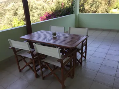 a wooden table and chairs on a balcony at Villa Christina Anidri in Ánidhroi