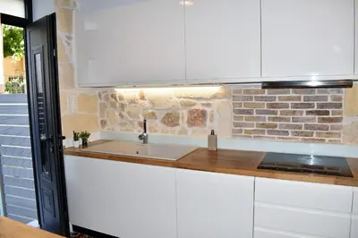 a white kitchen with a sink and a brick wall at The Well in Chania Town
