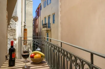 a glass of wine and a basket of fruit on a balcony at Penny's Old Town Houses in Chania Town