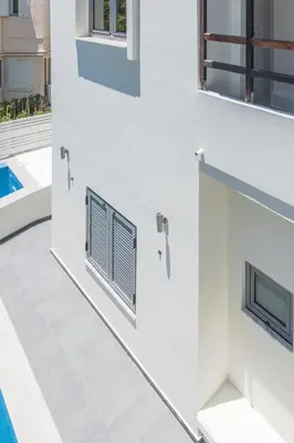 a white wall with two windows and a swimming pool at Rotunda Suites in Kalamaki Chanion