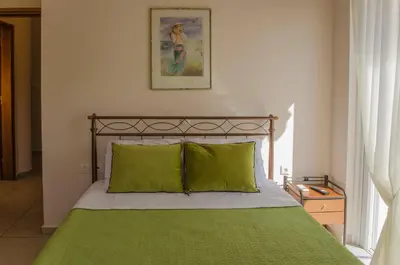 a bed with green sheets and pillows in a bedroom at Villa Aretaki in Kalamaki Chanion