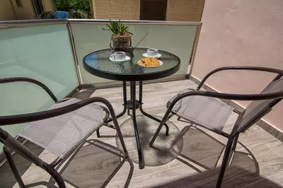 a table with two chairs and a plate of food on a balcony at Pasiphae New Apartment sea & city in Chania Town