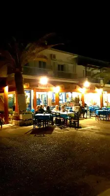 a group of people sitting at a restaurant at night at Christos Rooms in Palaiochóra