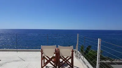 two chairs sitting on a balcony looking at the ocean at Christos Rooms in Palaiochóra