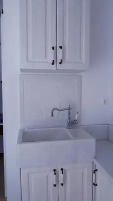 a white kitchen with a sink and white cabinets at Christos Rooms in Palaiochóra