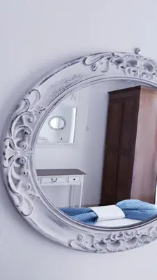 a mirror on a wall with a bed in a room at Christos Rooms in Palaiochóra