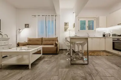 a kitchen and living room with a table and a couch at Chrisi Holiday Home - 500 sqm Private Gardens & Nature View - 300m by the sea in Almirida