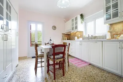 a kitchen with white cabinets and a table and chairs at House on the sea near Chania in Galatás
