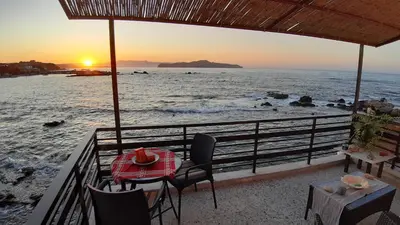 a table and chairs on the beach at sunset at House on the sea near Chania in Galatás