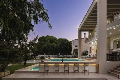 a house with a swimming pool and stools at Cedar Tree Villa in Kounoupidhianá
